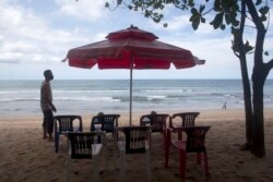 Seorang pedagang menyiapkan kursi sambil menunggu pelanggan di Pantai Kuta Bali, 14 Oktober 2021. (AP Photo/Firdia Lisnawati)