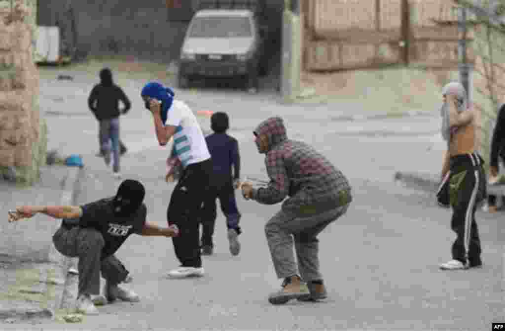 Palestinian youth throw stones at Israeli riot police, not seen, during a protest against Jewish settlements in the east Jerusalem neighborhood of Silwan, Monday, Dec. 27, 2010. Tensions regularly run high in Silwan, where a small group of Israeli settler
