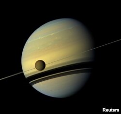 Titan, Saturn's largest moon appears before the planet as it undergoes seasonal changes in this natural color view from NASA's Cassini spacecraft in this handout released by NASA August 29, 2012. The moon measures 3,200 miles, or 5,150 kilometers, across