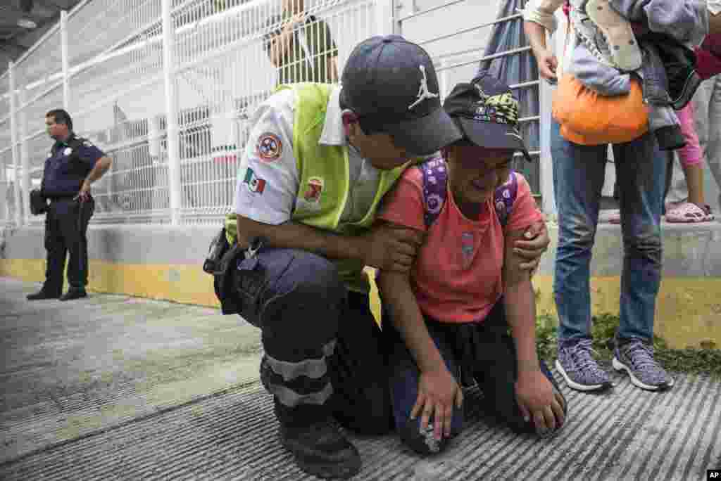 A Honduras migrant is comforted by a Mexican paramedic after her mother fainted while crossing the border between Guatemala and Mexico, in Ciudad Hidalgo, Mexico, Oct. 20, 2018. 