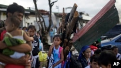 Những gia đình sống sót trong trận bão Haiyan chờ chuyến bay tại sân bay ở Tacloban, Philippines, để di tản, 21/11/13