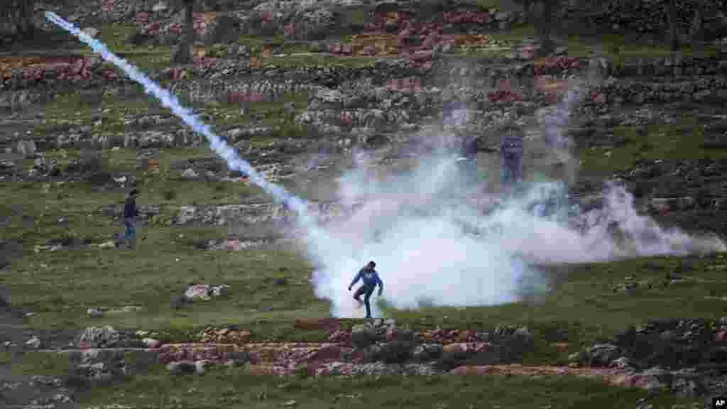 Demonstran Palestina melemparkan kembali gas air mata yang ditembakkan oleh tentara Israel di Ramallah, Tepi Barat.&nbsp;