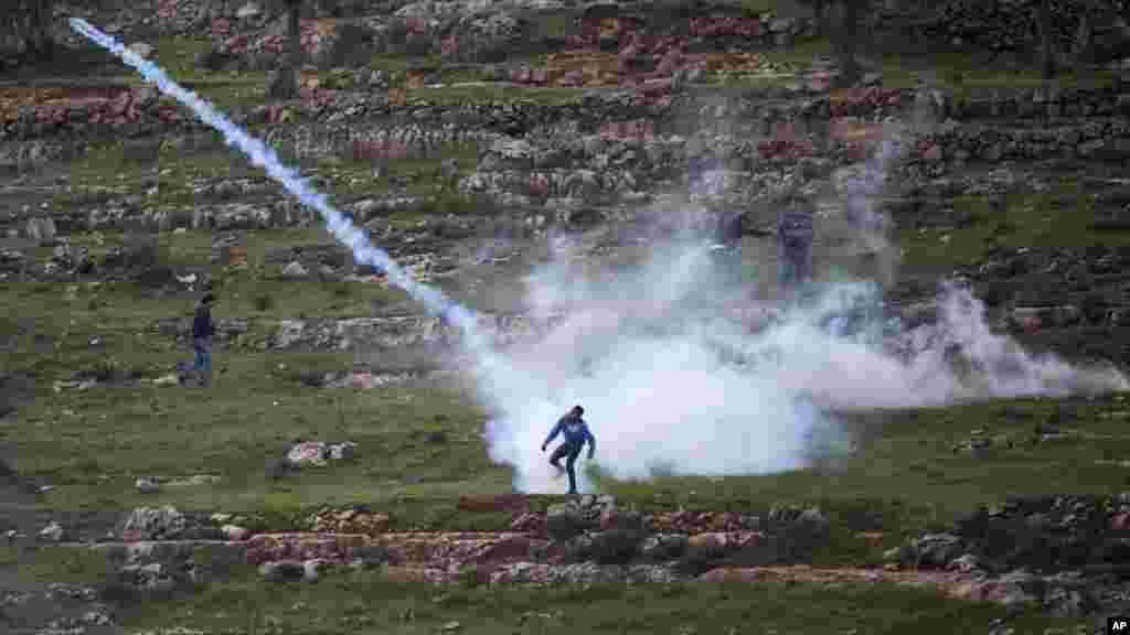 Demonstran Palestina melemparkan kembali gas air mata yang ditembakkan oleh tentara Israel di Ramallah, Tepi Barat. 