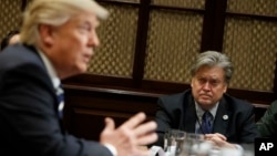 FILE - White House chief strategist Stephen Bannon listens at right as President Donald Trump speaks during a meeting in the Roosevelt Room of the White House in Washington. Trump on Wednesday removed Bannon from his role on the National Security Council.