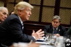 FILE - White House Chief Strategist Steve Bannon listens at right as President Donald Trump speaks during a meeting on cyber security in the Roosevelt Room of the White House in Washington.