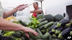 A woman buys cucumbers at a market in El Alquian, Almeria, in southeastern Spain, May 29, 2011