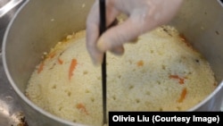 Ekber Kayser uses a chopstick to make holes in the rice as he prepares Uyghur polo, a rice pilaf.