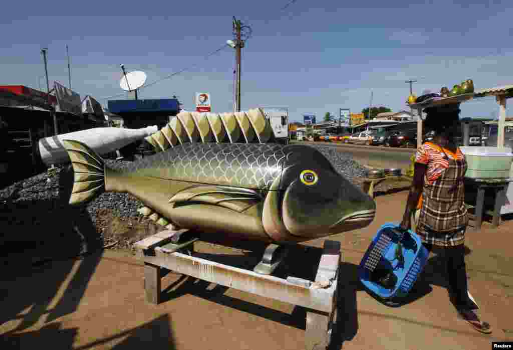 A street vendor passes a coffin made in the shape of a fish at the workshop of Kane Kwei in the Teshi area of Accra, Ghana, May 16, 2013. 