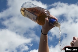 A woman pours alcohol from the bottle into her mouth, 2015. (File Photo)