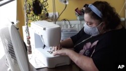 In this photo taken on Thursday, March 19, 2020, Sien Lagae, works on a mouth mask, meant to help protect agains the spread of Covid-19 at her sewing machine at her home at Torhout, Belgium