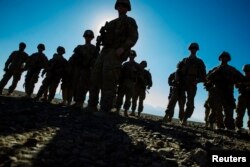 FILE - U.S. soldiers from Dragon Company of the 3rd Cavalry Regiment are silhouetted as they stand outside their vehicles during a mortar exercise near forward operating base Gamberi in the Laghman province of Afghanistan, Dec. 26, 2014.