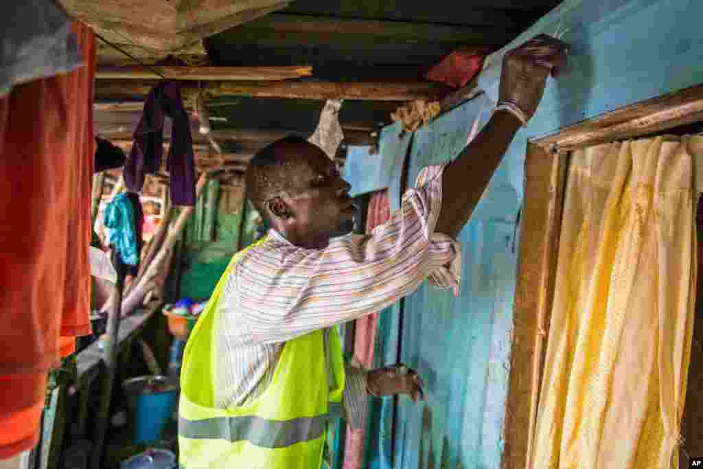 Um técnico de saúde voluntário marca uma casa com giz para identificar que foi visitada, enquanto são distribuídas barras de sabão e informação sobre o Ébola, Freetown, Serra Leoa, Set. 20, 2014. 