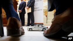 FILE- A model of a Mercedes-Benz sits in front of company officials as they wait to speak during a ceremony in Atlanta announcing the company's relocation of its U.S. corporate headquarters to Sandy Springs, Ga., from New Jersey, Feb. 3, 2015. German business leaders have expressed concerns that President Donald Trump's 25 percent tariff on imported steel could affect the auto industry in the South. 