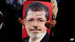 A supporter holds a poster of Egypt's Islamist President Mohammed Morsi with Arabic that reads, "Sisi traitor," during a rally, in Nasser City, Cairo, Egypt, July 4, 2013. 