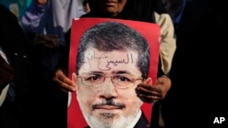 A supporter holds a poster of Egypt's Islamist President Mohamed Morsi with Arabic that reads, "Sisi traitor," during a rally, in Nasser City, Cairo, July 4, 2013.