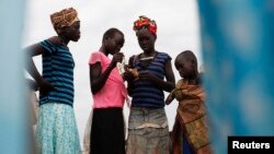 Girls check their ratio cards as they wait to receive food during food distribution in Minkaman, Lakes State, South Sudan, June 26, 2014. 