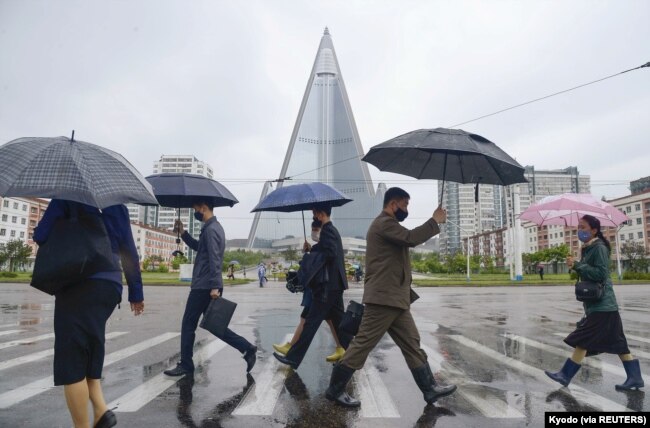 Orang-orang mengenakan masker berjalan di tengah kekhawatiran atas pandemi COVID-19 di Pyongyang, Korea Utara, 15 Mei 2020. ( Kyodo via REUTERS)