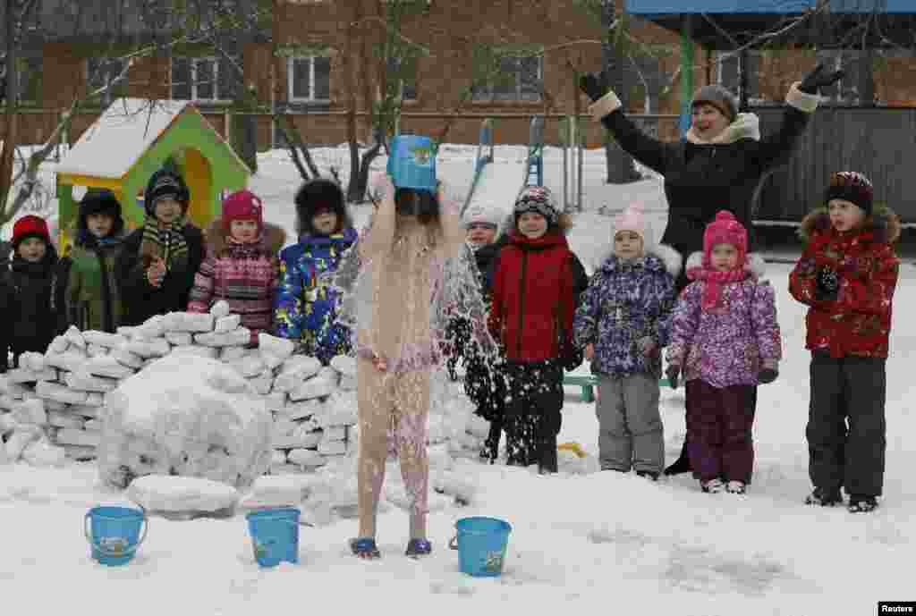 Anak-anak memperhatikan teman-temannya menyiramkan air dingin ke badan mereka sendiri, di bawah pengawasan pelatih Oksana Kabotko (tidak terlihat di foto), sebagai bagian dari program kesehatan dan kebugaran di taman kanak-kanak di Krasnoyarsk, Siberia, dengan suhu udara di bawah nol.