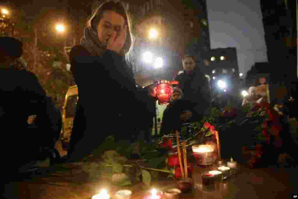 A woman lights a candle at the well-known military choir&#39;s building in Moscow, Russia, after a plane carrying 92 people, including 64 members of the Alexandrov Ensemble, crashed into the Black Sea minutes after taking off from the resort city of Sochi.