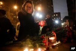 Une femme tient une bougie devant le bâtiment du choeur de l'armée rouge à Moscou, Russie, le 25 décembre 2016.