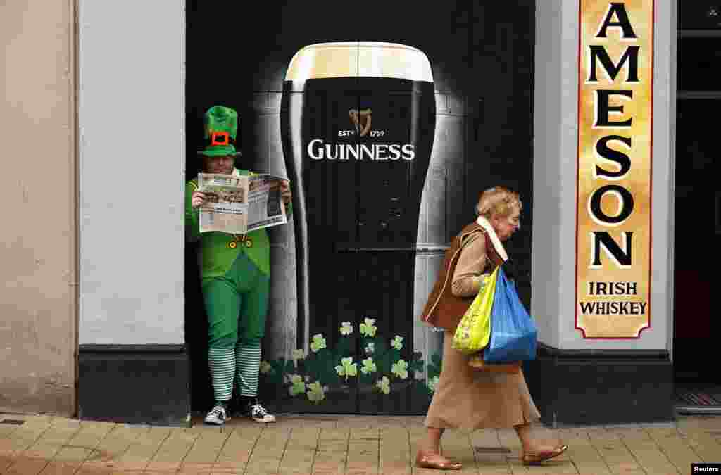 북아일랜드 런던데리에서 성 패트릭 축제를 앞두고 아일랜드 민화 속 요정 '레프러콘' 복장의 남성이 신문을 읽고 있다.