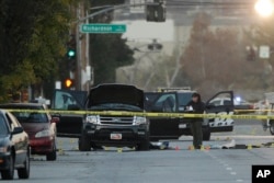 An investigator looks at a Black SUV that was involved in a police shootout with suspects, Dec. 3, 2015, in San Bernardino, Calif.