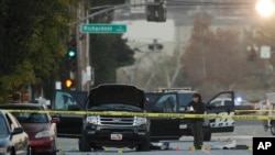 An investigator looks at a Black SUV that was involved in a police shootout with suspects, Dec. 3, 2015, in San Bernardino, Calif.