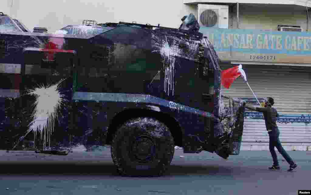 A protester, holding a Bahraini flag, confronts a riot police armored personnel carrier in an attempt to stop it from entering the village of Bilad Al Qadeem, south of Manama. Bahraini police fired rubber bullets and tear gas to scatter protesters who gathered outside the home of Sheikh Ali Salman, a Shi'ite Muslim opposition leader, witnesses said, after he was remanded in custody for a further 15 days.