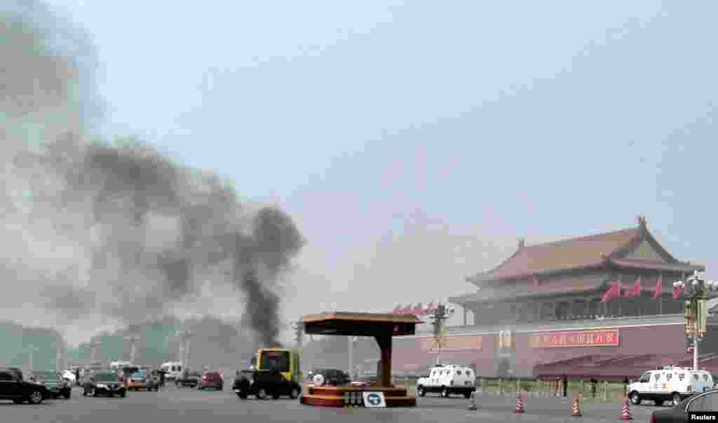 Xe cộ chạy dọc theo đại lộ Tràng An gần Quảng trường Thiên An Môn trong lúc lửa khói bốc lên từ chiếc xe tại một nơi không xa bức hình khổng lồ của Mao Trạch Đông. 