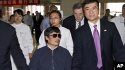 In this file photo taken May 2, 2012 and released by the US Embassy Beijing Press Office, blind activist Chen Guangcheng, center, holds hands with US Ambassador to China, Gary Locke, at a hospital in Beijing.