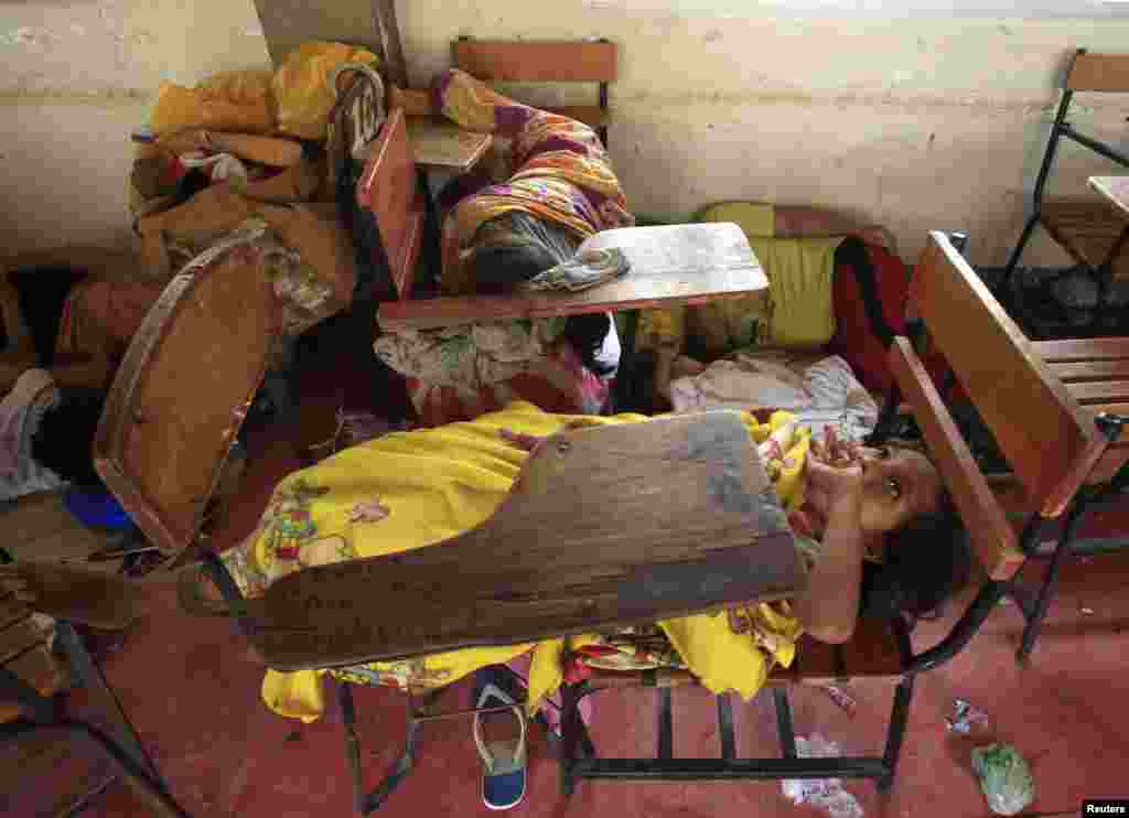 Seorang gadis kecil tidur telentang di atas kursi sekolah di dalam pusat evakuasi setelah Topan Rammasun menghantam pantai di Baseco, metro Manila (16/7). (Reuters/Romeo Ranoco)