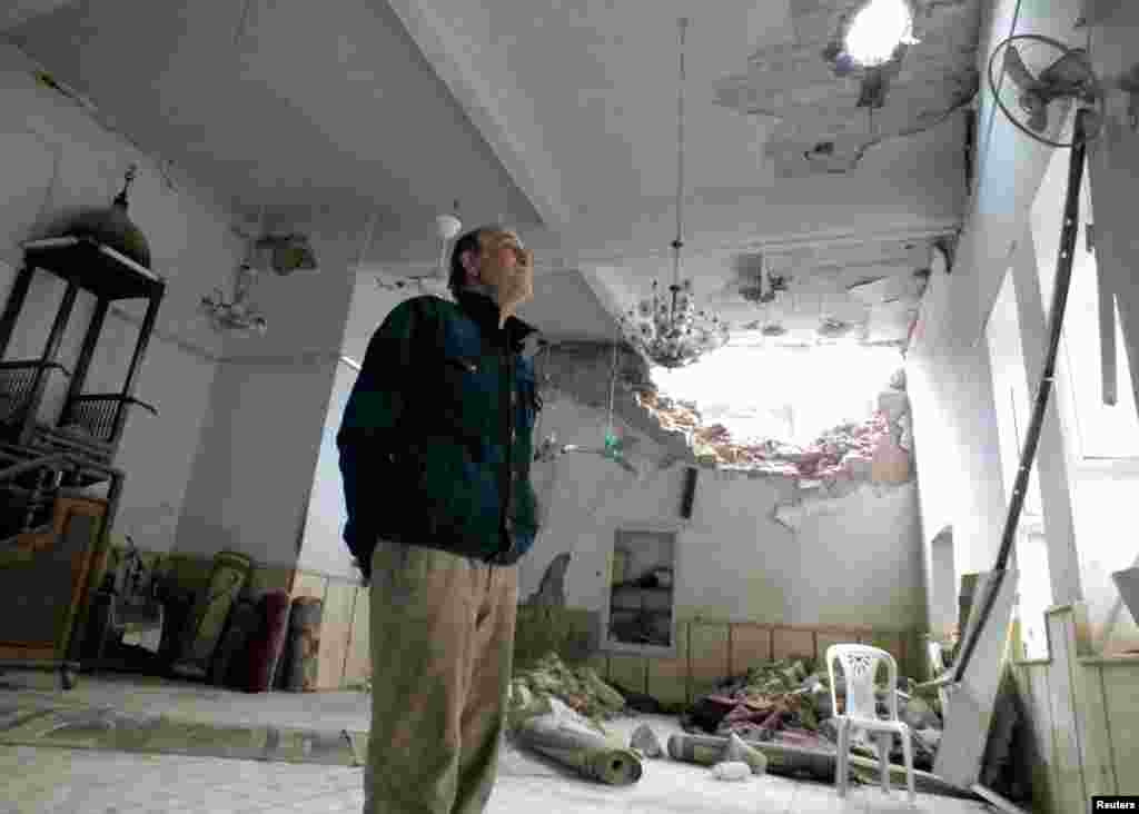 A man inspects the damaged interior of Al-fadail mosque in Homs, March 16, 2013.
