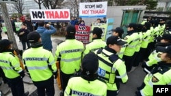 Police surround anti-war activists holding banners demonstrating against the Terminal High Altitude Area Defense (THAAD) anti-ballistic missile system outside the Foreign Ministry in Seoul, March 17, 2015. 