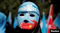 An ethnic Uighur demonstrator wears a mask as she attends a protest against China in front of the Chinese Consulate in Istanbul, Turkey, October 1, 2019. REUTERS/Huseyin Aldemir/File Photo - RC11CB775F30
