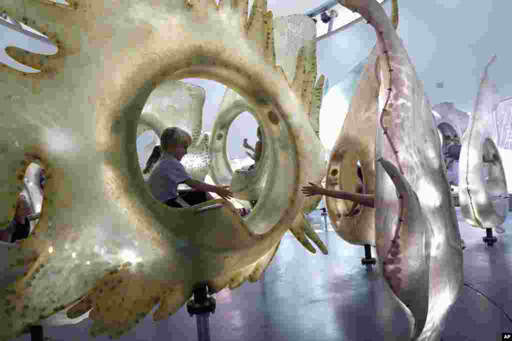 Children reach to each other while they ride the SeaGlass Carousel in New York&#39;s Battery Park, Aug. 23, 2016 .