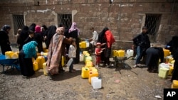 FILE - Women and children wait to fill buckets with water from a public tap amid an acute shortage of water, in Sana'a, Yemen, May 9, 2015. 