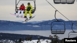 Snowboarders ride a lift with Lake Tahoe in the background at Squaw Valley in Olympic Valley, California, Dec. 5, 2015.