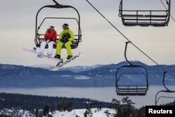 FILE - Snowboarders ride a lift with Lake Tahoe in the background at Squaw Valley in Olympic Valley, California, Dec. 5, 2015.