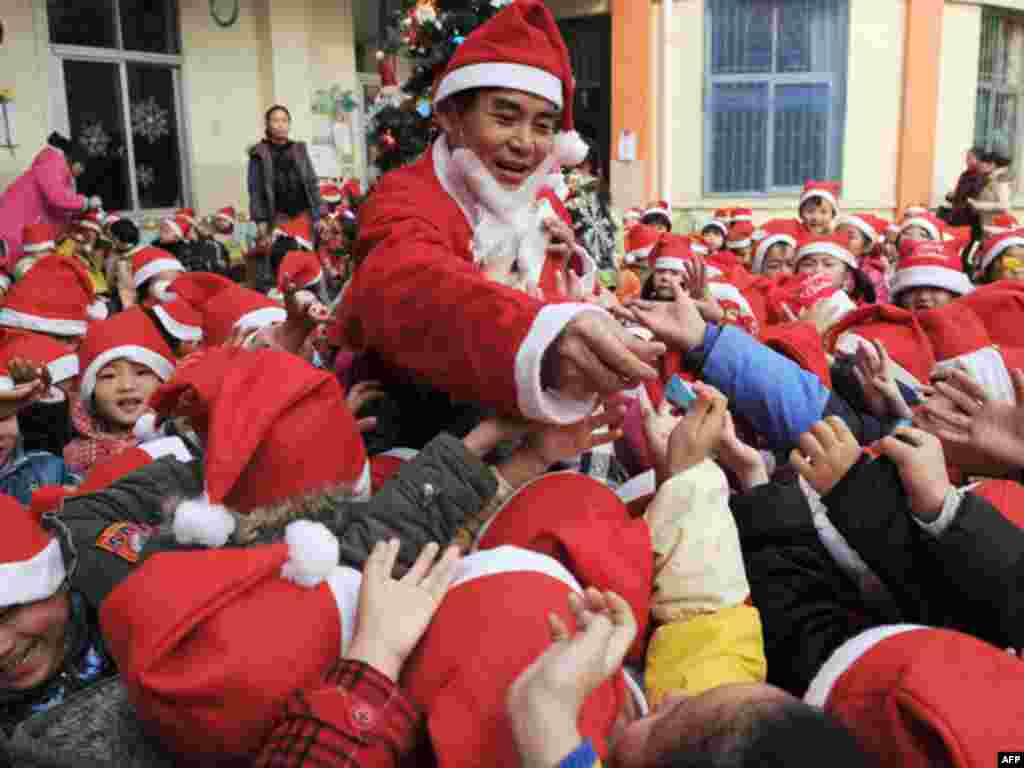 A teacher dressed as Santa Claus distributes candy to children to celebrate the upcoming Christmas Day at a kindergarten in Hefei, Anhui province December 23, 2010.