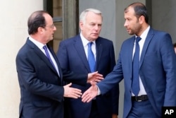 FILE - Then-French President Francois Hollande, left, flanked by his foreign minister, Jean Marc Ayrault, center, shakes hands with Rahed Saleh, director of Syrian Civil Defense White Helmets, after their meeting with a Syria delegation at the Elysee Palace, in Paris, Oct. 19, 2016.