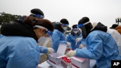 Medical workers wearing protective gear prepare to take samples at a temporary screening clinic for coronavirus in Seoul, South Korea, Dec. 10, 2021.