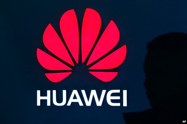 A man is silhouetted as he walks by a Huawei retail store at a shopping mall in Beijing, China, Dec. 11, 2018.
