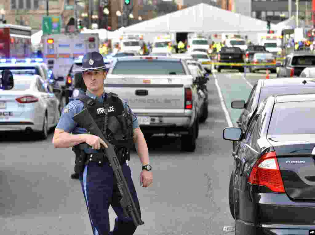 A Massachusetts state police officer guards the area containing the medical tent, rear, following an explosion at the 2013 Boston Marathon in Boston, Monday, April 15, 2013.