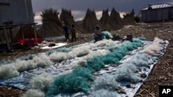 Naty Lugano Quispe cleans fish nets in Kapi Cruz Grande, a village on the shore of Lake Titicaca, in the Puno region of Peru, Feb. 4, 2017. 