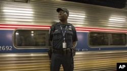 An Amtrak police officer stands guard outside Train 110, May 18, 2015, at Philadelphia's 30th Street Station. The train bound for New York was the first northbound train from the city since a May 12 derailment killed 8 people and injured dozens. 