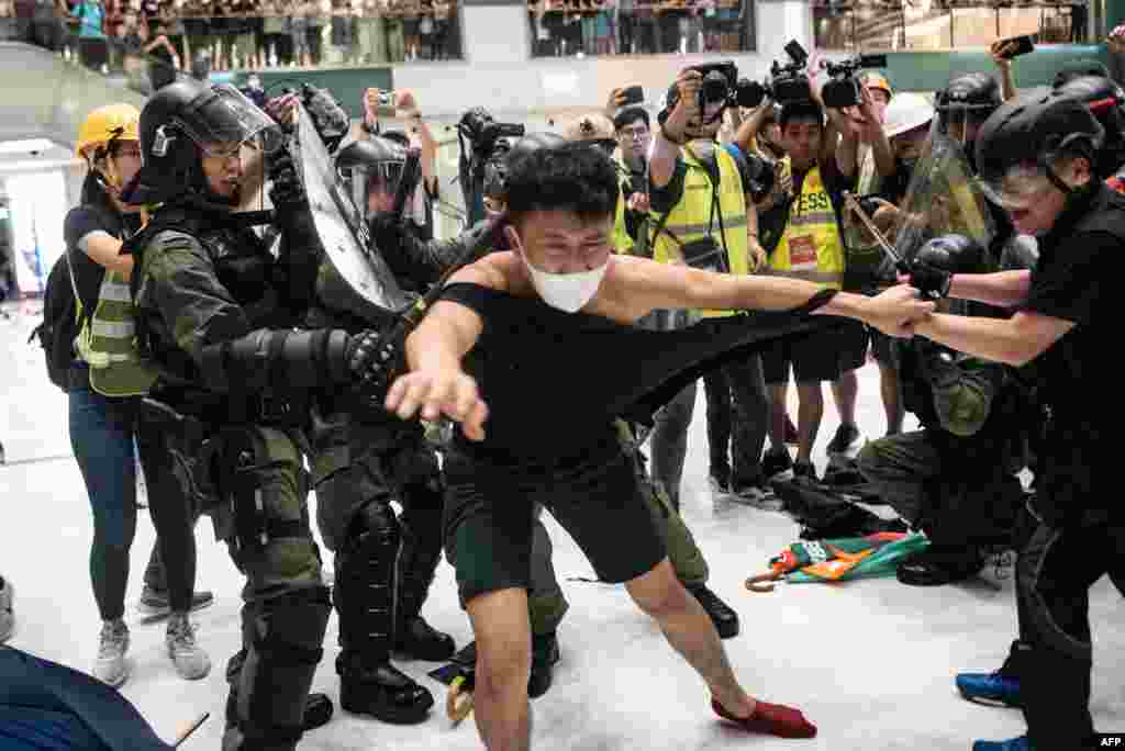 Police officers tear the shirt of a protester during a clash inside a shopping arcade in Sha Tin of Hong Kong after a rally against a controversial extradition law proposal in Sha Tin district.