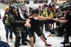 Police officers tear the shirt of a protester during a clash inside a shopping arcade in Sha Tin of Hong Kong after a rally against a controversial extradition law proposal in Sha Tin district of Hong Kong on July 14, 2019.