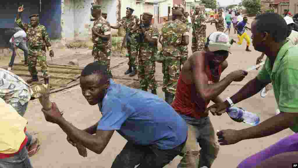 Des soldats tirent en l&#39;air pour disperser des manifestants qui ont acculé Jean Claude Niyonzima un membre présumé de la milice Imbonerakure de la jeunesse du parti au pouvoir dans un égout dans le quartier de Cibitoke de Bujumbura, au Burundi, jeudi 7 mai 2015.