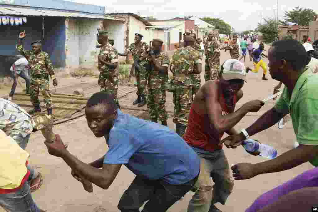 Des soldats tirent en l&#39;air pour disperser des manifestants qui ont acculé Jean Claude Niyonzima un membre présumé de la milice Imbonerakure de la jeunesse du parti au pouvoir dans un égout dans le quartier de Cibitoke de Bujumbura, au Burundi, jeudi 7 mai 2015.