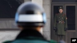 A North, right, and a South Korean soldier look at each other's sides at the Panmunjom (DMZ) that separates the two Koreas since the Korean War, in Paju, South Korea, December 28, 2011.